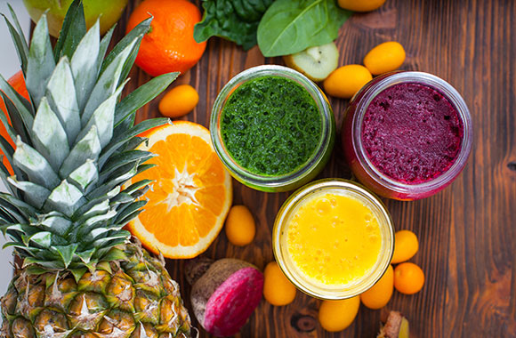 Blended green,yellow and purple smoothie with ingredients selective focus