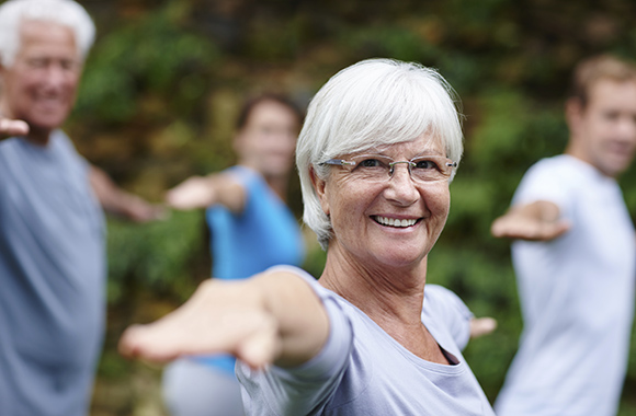 Shot of a senior woman doing yoga with other people outdoors